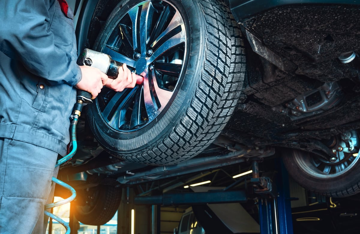 Mechanic removing a wheel from a vehicle raised on a hoist at the Ignition Tyre & Auto workshop